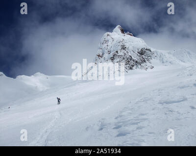 Un snowboarder solitaire fait son chemin jusqu'à Carter Rock, un vieux lave dome, sur Mt. Comme les nuages de la hotte à proximité. Payer pour vous tourner. Banque D'Images