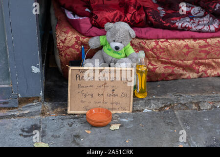 Une personne sans-abri et les possessions de literie dans l'embrasure d'une boutique sur une rue de la ville, et une note écrite, demander de l'aide à payer pour le gîte Banque D'Images