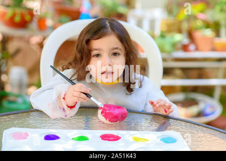 Portrait du petit enfant, la peinture en plein air d'été.Kid dessin sur une pierre. Banque D'Images