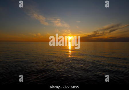 Le soleil se couche dans un coucher de soleil colorés reflètent dans l'océan Atlantique par beau temps par Nantucket Island, Cape Cod, Massachusetts, New England, USA Banque D'Images