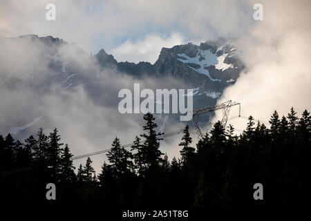 Contraste entre les lignes à haute tension et les sommets de montagnes couvertes de neige derrière. Banque D'Images