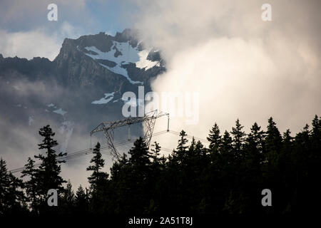 Contraste entre les lignes à haute tension et les sommets de montagnes couvertes de neige derrière. Banque D'Images