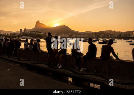 Belle vue sur le coucher de soleil de sociabilisation des amis et boire à l'océan à pied dans Mureta da Urca avec la montagne du Corcovado à l'arrière, Rio de Janeiro, Bra Banque D'Images