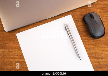 Bureau de travail en bois minimal avec page vierge, espace de copie, stylo, ordinateur portable, souris. Vue de dessus, espace texte, maquette. Bureau. Banque D'Images