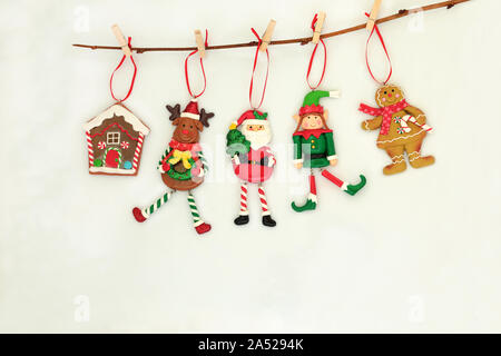 Décorations de Noël suspendu à une branche avec le père Noël, les rennes, Elf, gingerbread house et cookie dame sur fond crème avec copie espace. Banque D'Images