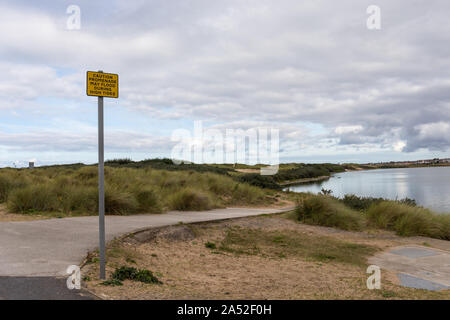 Attention la promenade peut inonder pendant les hautes marées panneau d'avertissement à Crosby Lakeside Adventure Center, Merseyside, Royaume-Uni Banque D'Images