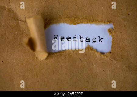 Le texte, commentaires, apparaît derrière le papier marron déchiré Banque D'Images