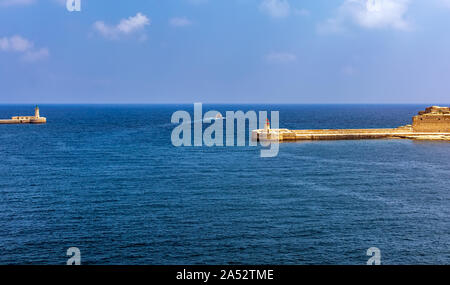 Bateau dans la mer turquoise de l'eau entre La Valette avec brise-lames et phare lumière Breakwater Ricasoli à Grand Harbour East brise-lames. Banque D'Images