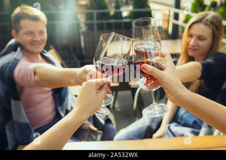 Les gens clinking glasses avec du vin sur la terrasse d'un café ou d'un restaurant. Happy woman fêtez l'été ou l'automne fest. Gros plan de mains humaines, de vie. Banque D'Images