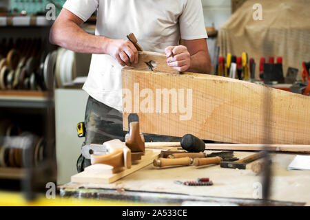 Carpenter panneaux d'un bloc de bois avec une scie manuelle ou la réduction de la surface de lissage avec différents outils dans l'avant-plan dans un bois worksho Banque D'Images