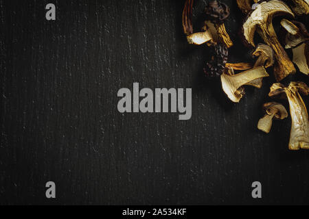 Tranches de champignons séchés savoureux sur fond noir en noir. Vue d'en haut. Banque D'Images