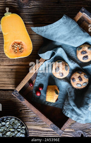 Muffins faits maison potiron sucré avec des canneberges séchées et graines, saupoudrées de sucre en poudre sur fond de bois Banque D'Images