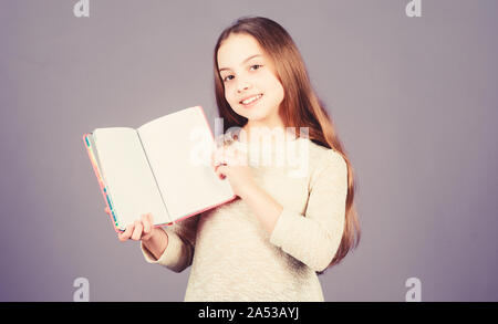 L'application de son livre à la connaissance du monde réel. Adorable petite fille tenant un livre ouvert. Enfant mignon petit livre avec la connaissance dans les mains. Compétences Connaissances. Jour des connaissances ou le 1 septembre, l'espace de copie. Banque D'Images