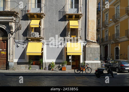 Une scène de rue en Italie montrant un café, avec un vélo et un scooter à l'extérieur et stores dans la lumière du soleil forte Banque D'Images