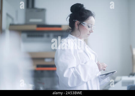 Femelle jeune scientifique avec le comprimé dans un laboratoire Banque D'Images