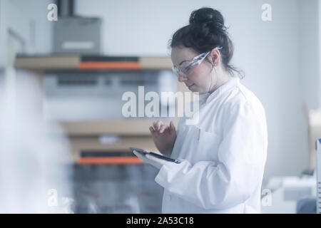 Femelle jeune scientifique avec le comprimé dans un laboratoire Banque D'Images