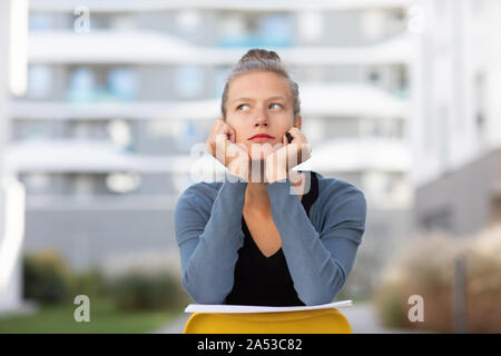 Jeune femme à l'extérieur assis sur une chaise en arrière Banque D'Images