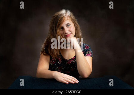 Studio shot of Horizontal un pré-ado jeune dame à écouter quelqu'un parler. Sa tête est posée sur sa main et est légèrement incliné d'un côté Banque D'Images