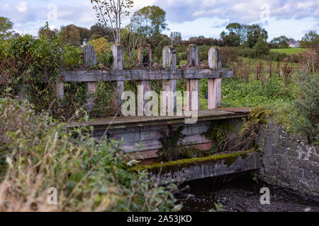 Un vieux bois envahi par la porte d'écluse de contrôle de l'eau Débit d'eau une vieille qui aurait tourné une roue du moulin Banque D'Images