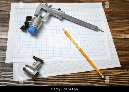 Un grand vernier couché sur papier La section transversale avec deux vannes à bille et d'un crayon sur la table en bois situé à côté de l'arrière-plan. Banque D'Images