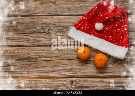 Arrière-plan en bois avec mandarines et chapeau de Noël sur la table. Cadre vacances d'hiver. Vue de dessus de la couche à plat. Espace de copie Banque D'Images