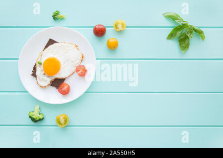 Toasts de pain de seigle avec les œufs et les légumes : tomates cerises, brocolis et feuilles de basilic frais sur fond de table turquoise. Copier l'espace, l'espace pour Banque D'Images