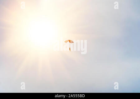 Sous couvert de parachutiste peu un parachute sur l'arrière-plan un soleil et un ciel bleu. Silhouette de la parachutiste avec parachute contre la surbrillance. Banque D'Images