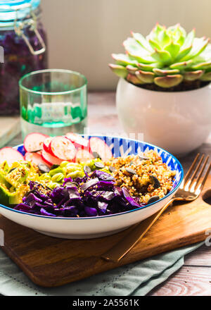 Bol Bouddha avec des couleurs arc-en-ciel - avocat ingrédients fermentés, du chou rouge, quinoa, radis, haricots verts, le sésame et les graines de citrouille. Servie sur wo Banque D'Images