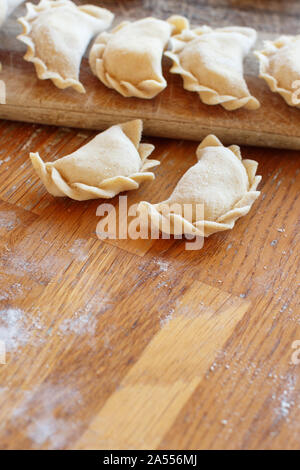 La viande crue pelmeni, ravioli, boulettes sur une planche en bois Banque D'Images