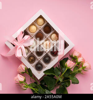 Les chocolats de divers chocolat belge dans une ambiance festive fort sur un fond rose et un bouquet de roses. Dessert exclusif cadeau. Maison de concept. Squar Banque D'Images