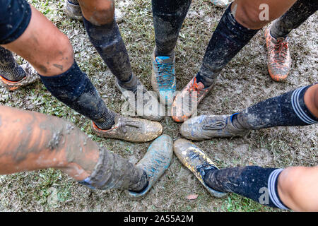 Adolescent Girls mettre leurs pieds ensemble pour montrer leurs chaussures de foot couvert de boue au cours de leur match de soccer Banque D'Images