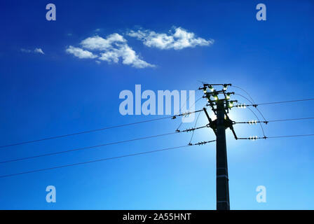 Pole et les isolateurs de ligne sur fond de ciel bleu. Banque D'Images