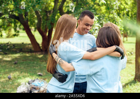 Le volontariat. Les jeunes bénévoles à l'extérieur hugging smiling happy d'équipe Banque D'Images