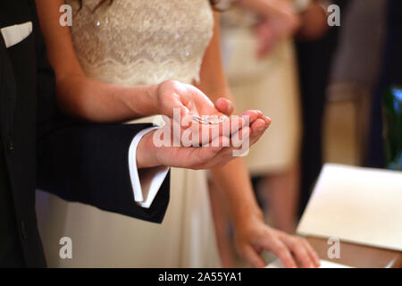 Les mains de l'époux et épouse tenir les anneaux de mariage en face de l'autel Banque D'Images