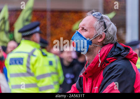 Londres, Royaume-Uni. 18 Oct, 2019. Un cycliste à un masque de smog, qui ne fait pas partie de la protestation, attend d'être laissé à travers les feux de circulation - bloc brièvement manifestants Oxford Circus avec un trépied et la police arrive rapidement avec un JCB à les retirer et procéder à des arrestations - la deuxième semaine de l'extinction qui a action Octobre Rébellion ont bloqué les routes dans le centre de Londres, mais a été en grande partie effacée. Ils sont une nouvelle fois en lumière l'urgence climatique, avec le temps presse pour sauver la planète d'une catastrophe climatique. Crédit : Guy Bell/Alamy Live News Banque D'Images