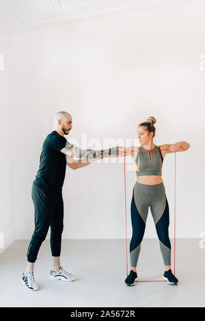 L'enseignement de l'instructeur de Fitness Femme en utilisant la résistance groupe en studio Banque D'Images