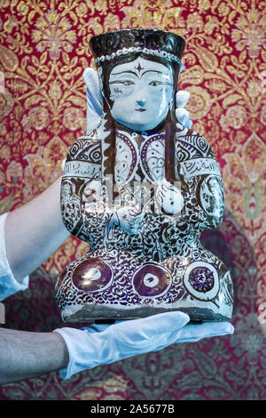 Londres, Royaume-Uni. 18 octobre 2019. Un technicien établit le «Kashan lustre pottery navire sous la forme d'une femme assis ruler', Perse, 12ème/13ème siècle (est. 10,000-15,000 GBP). Aperçu de l'Islam, Affaires indiennes et du Moyen-Orient l'art à être mis aux enchères à Sotheby's, New Bond Street, les 22 et 23 octobre. Crédit : Stephen Chung / Alamy Live News Banque D'Images