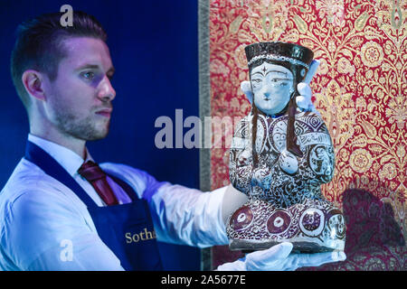 Londres, Royaume-Uni. 18 octobre 2019. Un technicien établit le «Kashan lustre pottery navire sous la forme d'une femme assis ruler', Perse, 12ème/13ème siècle (est. 10,000-15,000 GBP). Aperçu de l'Islam, Affaires indiennes et du Moyen-Orient l'art à être mis aux enchères à Sotheby's, New Bond Street, les 22 et 23 octobre. Crédit : Stephen Chung / Alamy Live News Banque D'Images