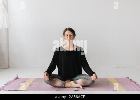 Woman sitting in lotus pose dans le studio de yoga Banque D'Images