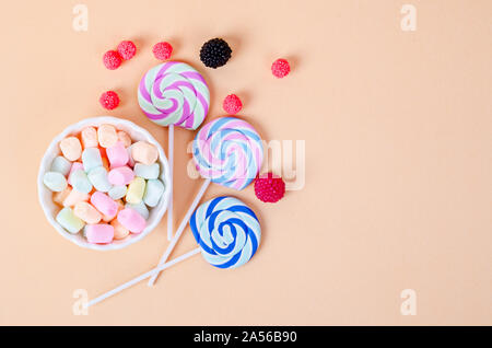 Guimauve colorée en blanc tasse et bonbons sur fond orange pastel. Mise à plat, vue du dessus Banque D'Images