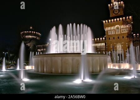 Plan horizontal de fontaines avec lumières devant un bâtiment italien la nuit à Milan, Italie Banque D'Images