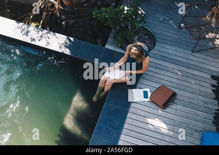 Businesswoman working on bord de piscine avec les jambes dans l'eau Banque D'Images