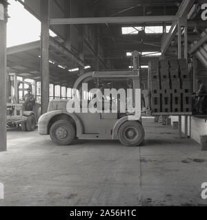 Années 1950, historique, un ouvrier exploitant un chariot élévateur électrique alors qu'il ramassait des briques récemment cuites à la brique de la London Brick Company (LBC) à Stewartby, Bedfordshire, Angleterre, Royaume-Uni. À cette époque, les briques étaient les plus grandes d'Europe. Banque D'Images