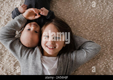 Girl joue contre joue avec bébé frère sur le lit, d'un portrait Banque D'Images