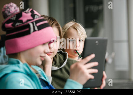 Girl et frères looking at digital tablet in airport, tête et épaules Banque D'Images