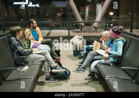 Homme mature avec fils et fille en attente dans la salle d'embarquement de l'aéroport de manger des collations