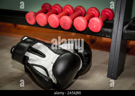 Pour la remise en forme et d'haltères rouge noir et blanc des gants de boxe sur le sol. Banque D'Images