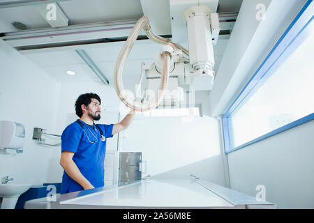 Jeune homme manipulateur en préparation dans la machine à rayons X, au département de radiologie Banque D'Images