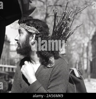 1950s, historique, un jeune artiste barbu aux cheveux longs à Montmartre, portant un tas de bâtons sur son dos, Paris, France. Banque D'Images