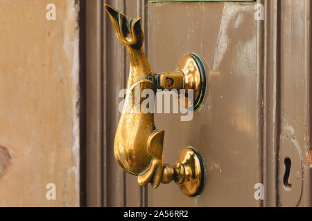 Heurtoir laiton forme de dolphin sur de vieilles portes brun Banque D'Images